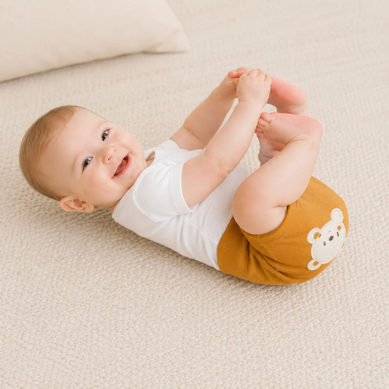 Bebê vestindo shorts saruel suedine na cor mostarda, deitado de lado — NinaBoo ref. 5117